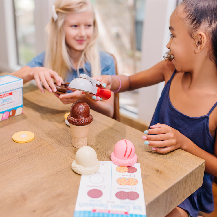 A kid playing with The Melissa & Doug Scoops and Sandwiches 13-Piece Ice Cream Play Food Set