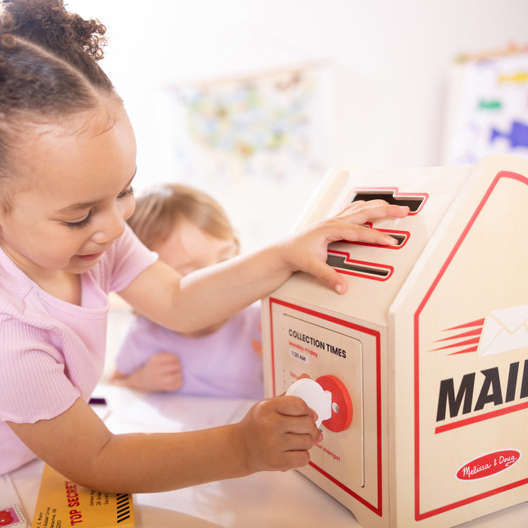 A kid playing with The Stamp and Sort Mailbox Play Set