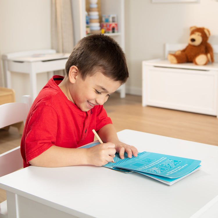 A kid playing with The Melissa & Doug On the Go Scratch Art Sea Life Color-Reveal 12-Page Activity Pad Creative Play for Boys and Girls Ages 5+