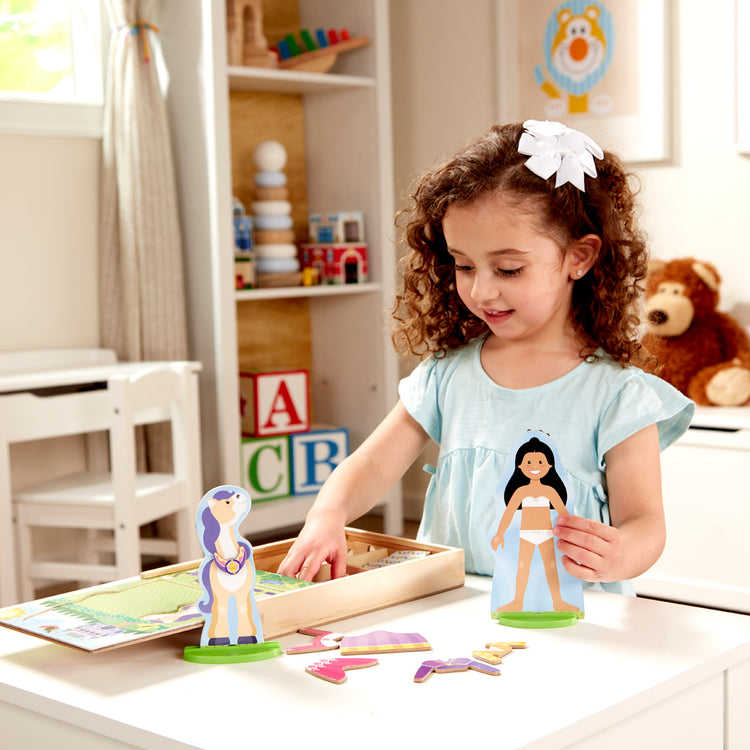 A kid playing with The Melissa & Doug Princess & Horse Magnetic Pretend Play Wooden Dolls Pretend Play Set (35 pcs)