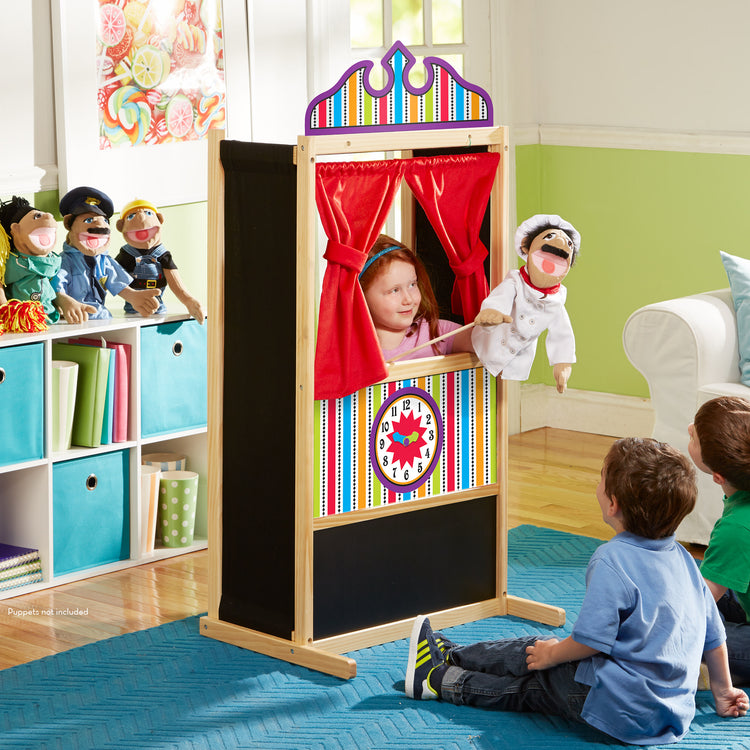 A kid playing with The Melissa & Doug Deluxe Puppet Theater - Sturdy Wooden Construction