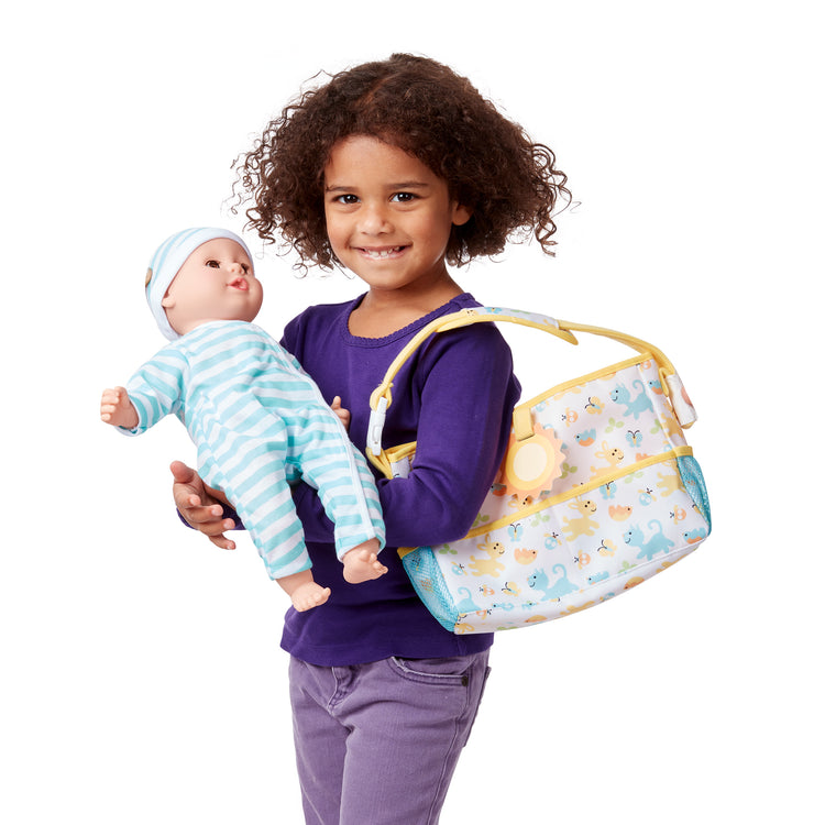 A child on white background with The Melissa & Doug Mine to Love Travel Time Play Set for Dolls with Diaper Bag, Bottle, Sunscreen, More (17 pcs)