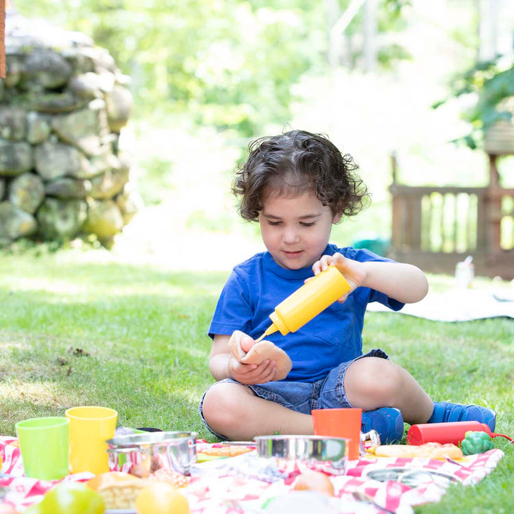 A kid playing with The Melissa & Doug Condiments Play Set (6 pcs) - Play Food, Stainless Steel Caddy