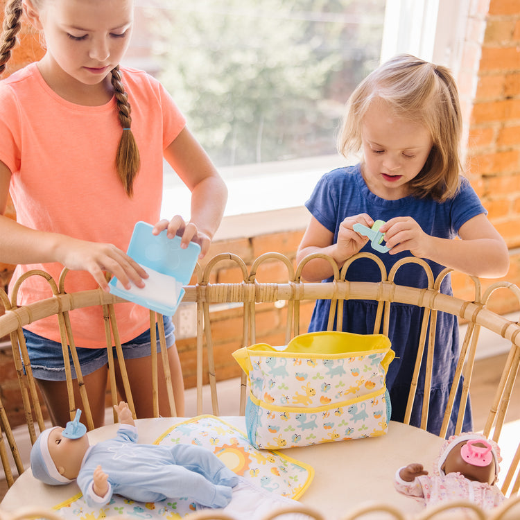 A kid playing with The Melissa & Doug Mine to Love Travel Time Play Set for Dolls with Diaper Bag, Bottle, Sunscreen, More (17 pcs)