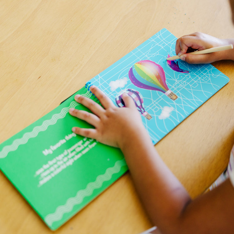 A kid playing with The Melissa & Doug On the Go Scratch Art Hidden-Picture Pad - Favorite Things