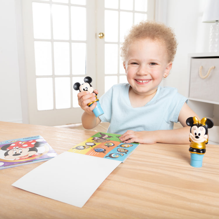 A kid playing with The Melissa & Doug Sticker WOW! Disney Special Edition Pack with Mickey & Minnie Stampers and 900 Stickers - Ages 3+