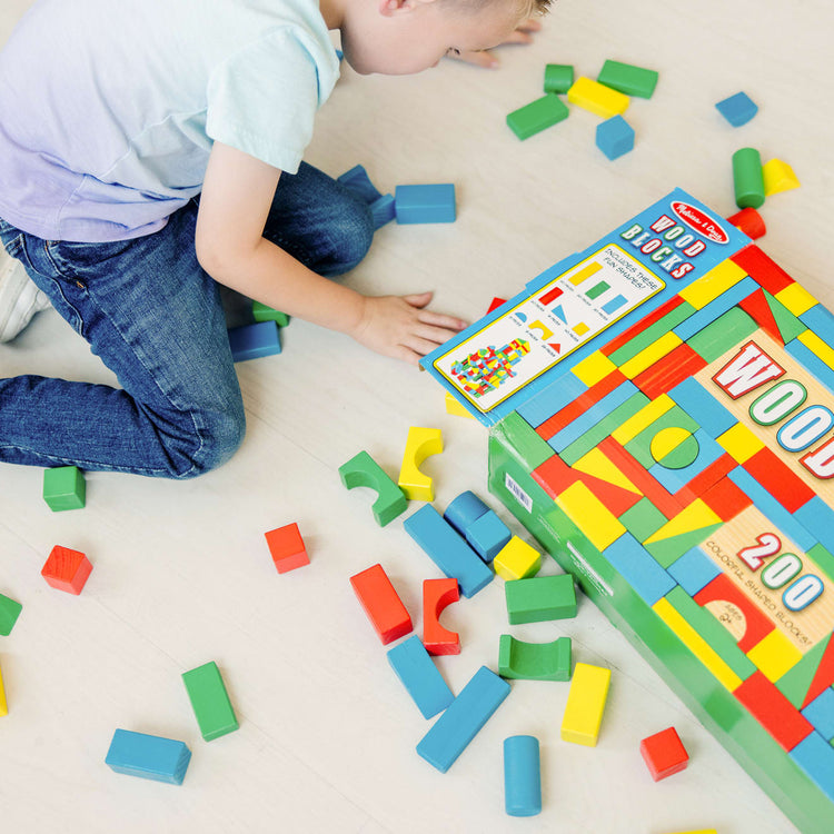 A kid playing with the Melissa & Doug Wooden Building Block Set - 200 Blocks in 4 Colors and 9 Shapes