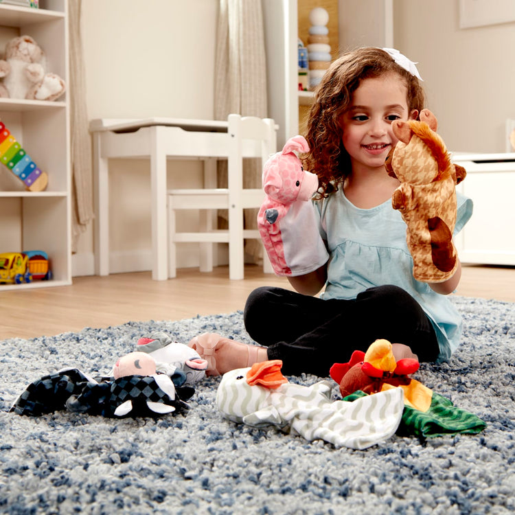 A kid playing with the Melissa & Doug Barn Buddies Hand Puppets, Set of 6 (Cow, Sheep, Horse, Duck, Chicken, Pig)