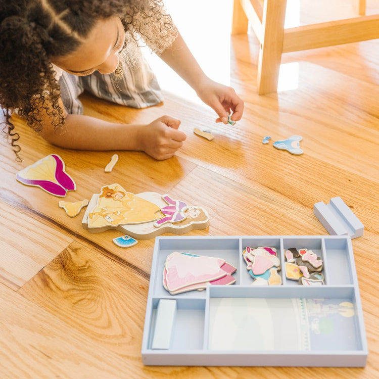 A kid playing with the Melissa & Doug Disney Belle Magnetic Dress-Up Wooden Doll Pretend Play Set