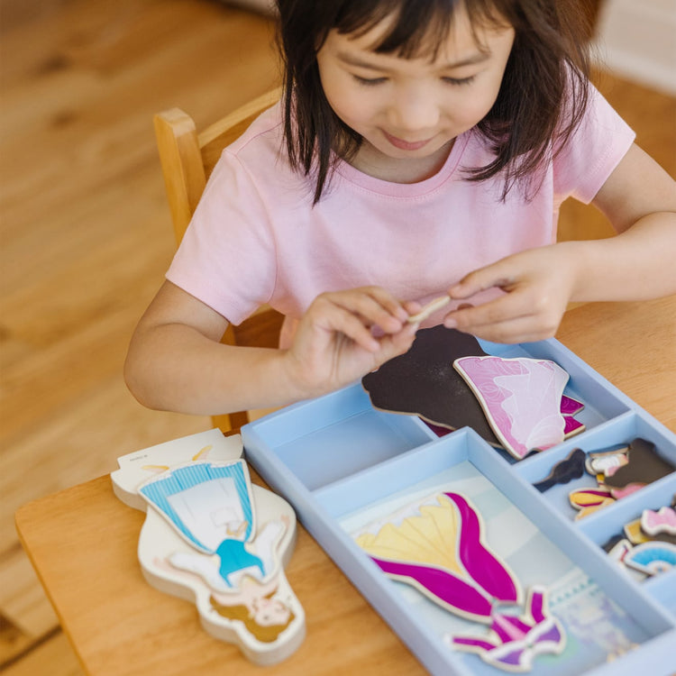 A kid playing with the Melissa & Doug Disney Belle Magnetic Dress-Up Wooden Doll Pretend Play Set