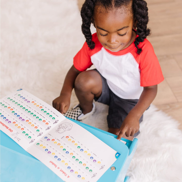 A kid playing with the Melissa & Doug Learn-to-Play Piano With 25 Keys and Color-Coded Songbook - Blue