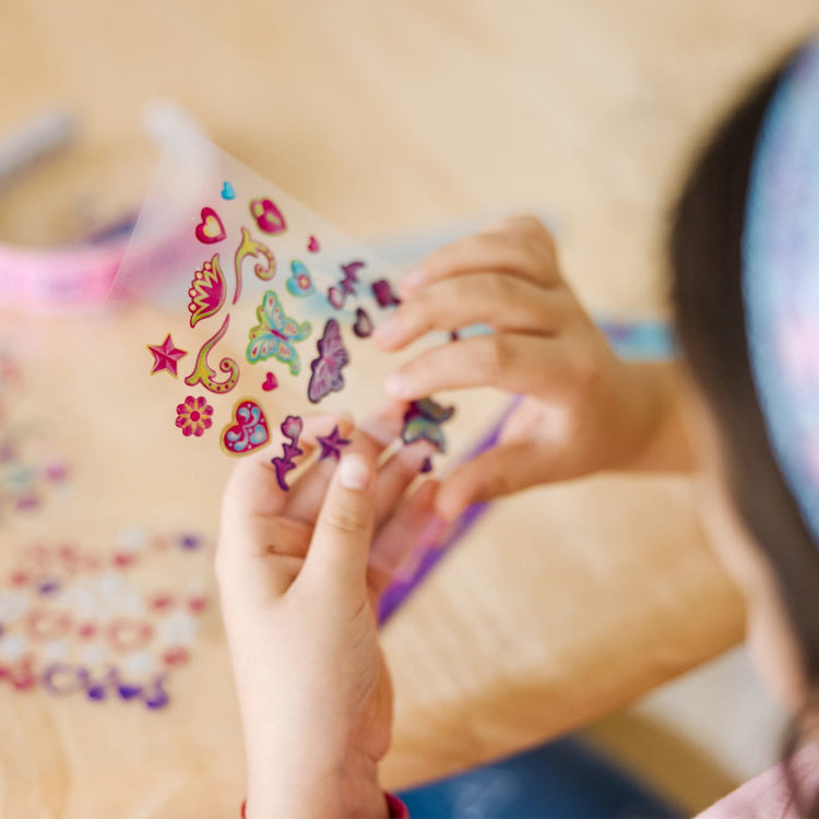 A kid playing with the Melissa & Doug Design-Your-Own Jewelry-Making Kits - Bangles, Headbands, and Bracelets