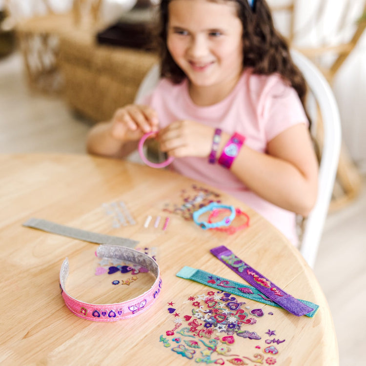A kid playing with the Melissa & Doug Design-Your-Own Jewelry-Making Kits - Bangles, Headbands, and Bracelets
