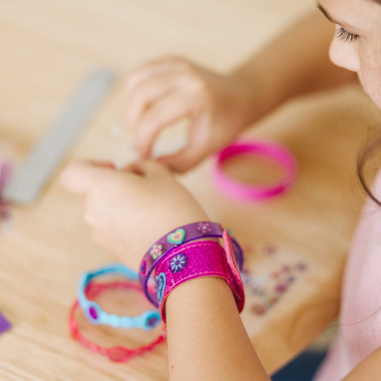 A kid playing with the Melissa & Doug Design-Your-Own Jewelry-Making Kits - Bangles, Headbands, and Bracelets