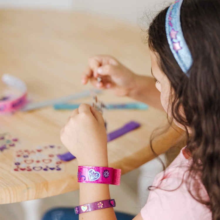 A kid playing with the Melissa & Doug Design-Your-Own Jewelry-Making Kits - Bangles, Headbands, and Bracelets