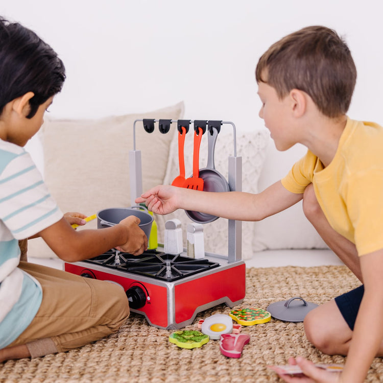 A kid playing with the Melissa & Doug 19-Piece Deluxe Wooden Cooktop Set With Wooden Play Food, Durable Pot and Pan