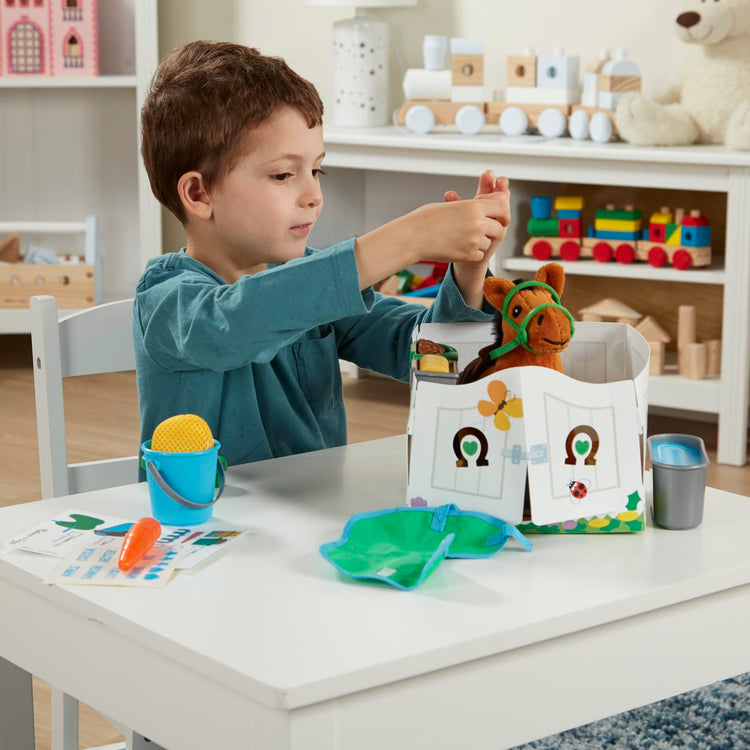 A kid playing with the Melissa & Doug Feed & Groom Horse Care Play Set With Plush Stuffed Animal (23 pcs)