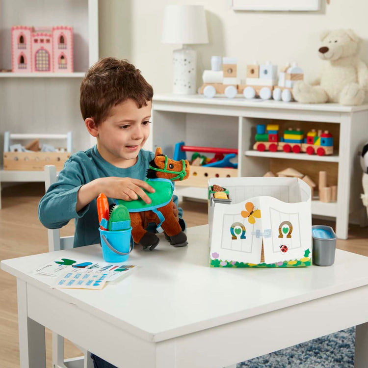 A kid playing with the Melissa & Doug Feed & Groom Horse Care Play Set With Plush Stuffed Animal (23 pcs)