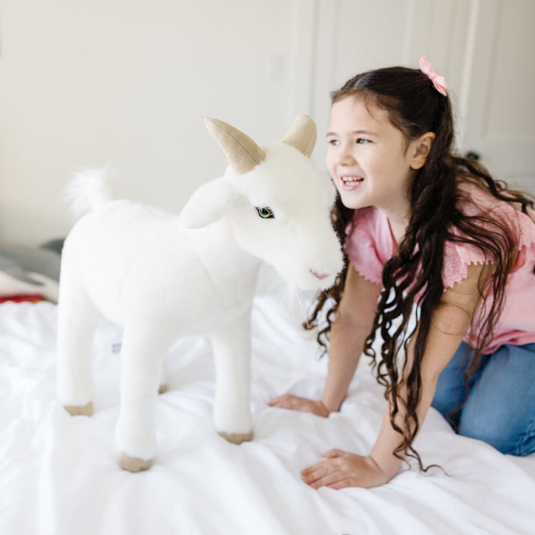 A kid playing with the Melissa & Doug Giant Goat - Lifelike Stuffed Animal (22.5 inches tall)