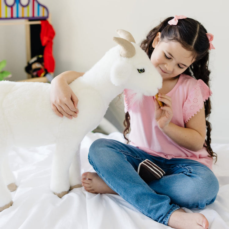 A kid playing with the Melissa & Doug Giant Goat - Lifelike Stuffed Animal (22.5 inches tall)