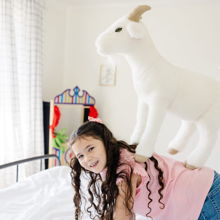 A kid playing with the Melissa & Doug Giant Goat - Lifelike Stuffed Animal (22.5 inches tall)