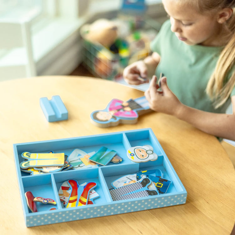 A kid playing with the Melissa & Doug Julia Magnetic Dress-Up Wooden Doll Pretend Play Set (25+ pcs)