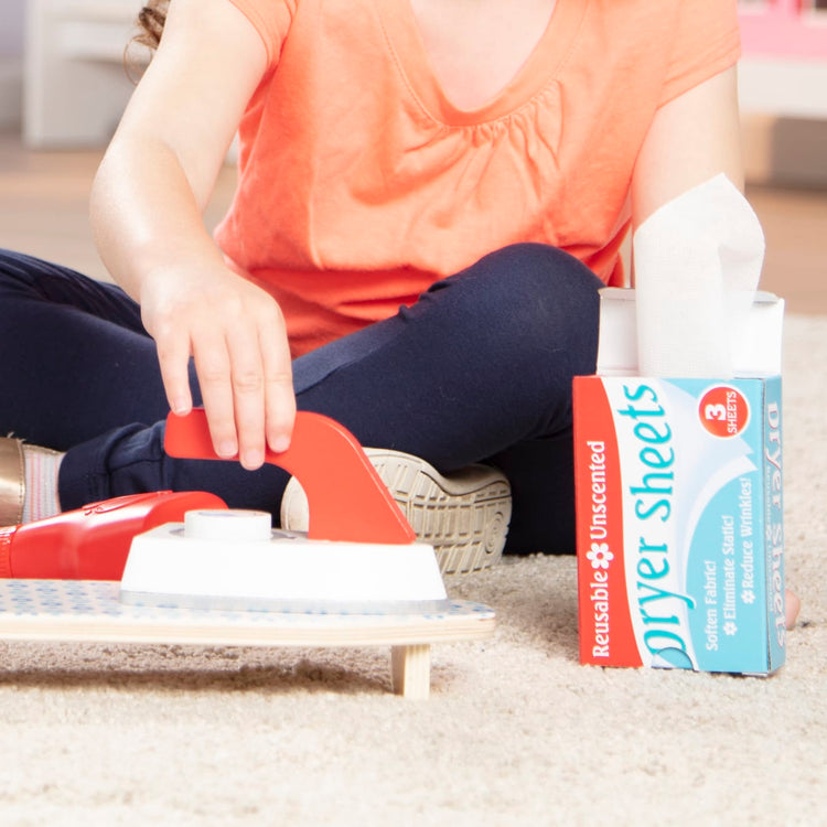 A kid playing with the Melissa & Doug Laundry Basket Play Set With Wooden Iron, Ironing Board, and Accessories (14 Pcs)