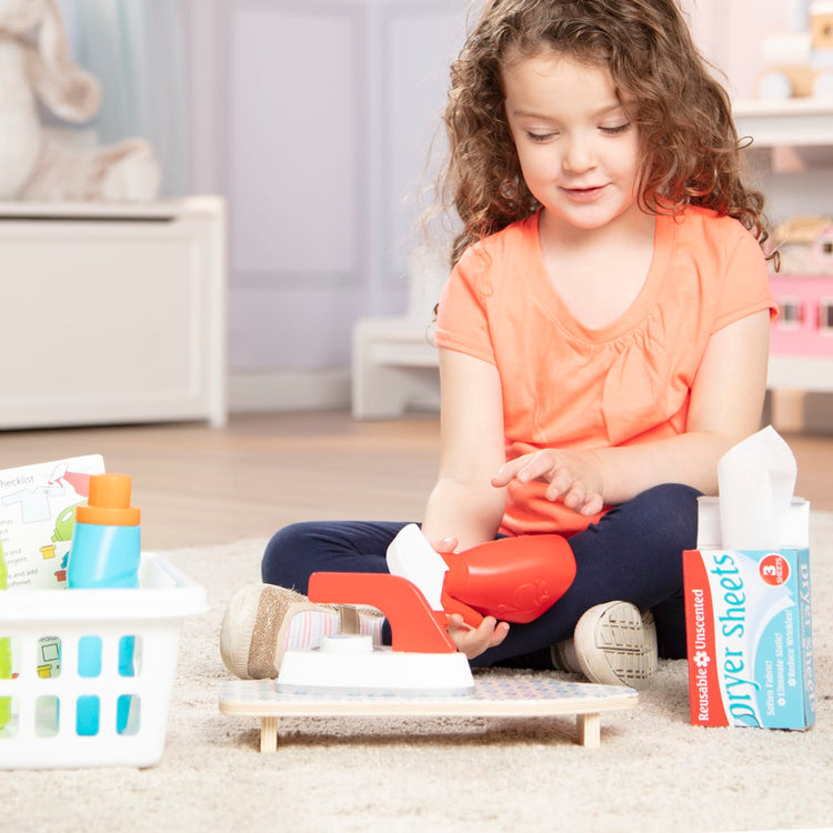 A kid playing with the Melissa & Doug Laundry Basket Play Set With Wooden Iron, Ironing Board, and Accessories (14 Pcs)
