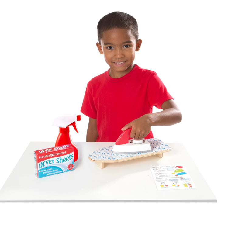A child on white background with the Melissa & Doug Laundry Basket Play Set With Wooden Iron, Ironing Board, and Accessories (14 Pcs)