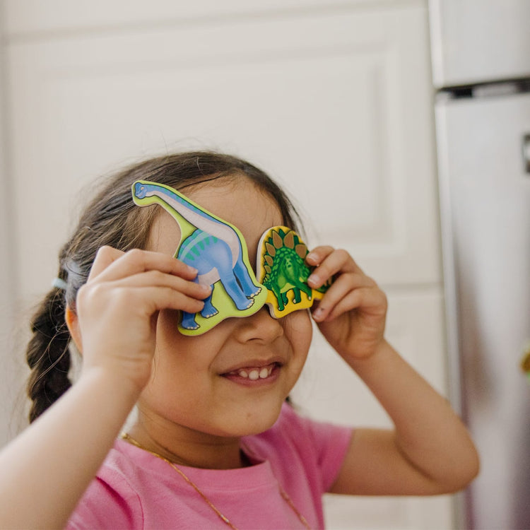 A kid playing with the Melissa & Doug Wooden Magnets Set - Animals and Dinosaurs With 40 Wooden Magnets