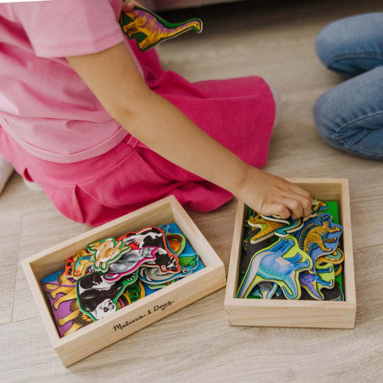 A kid playing with the Melissa & Doug Wooden Magnets Set - Animals and Dinosaurs With 40 Wooden Magnets