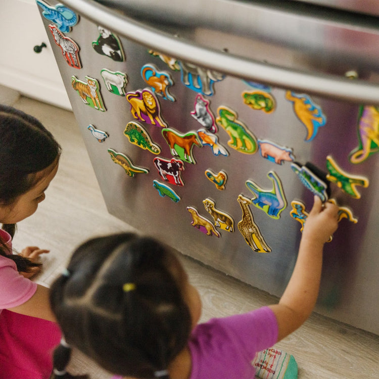 A kid playing with the Melissa & Doug Wooden Magnets Set - Animals and Dinosaurs With 40 Wooden Magnets