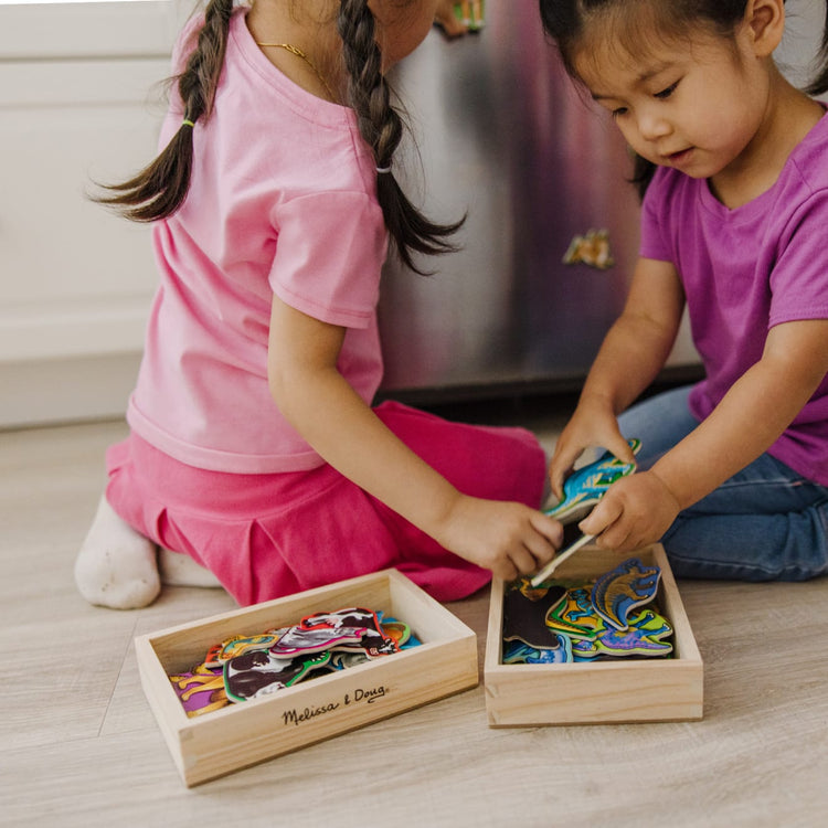 A kid playing with the Melissa & Doug Wooden Magnets Set - Animals and Dinosaurs With 40 Wooden Magnets