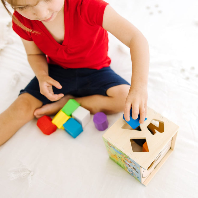A kid playing with the Mickey Mouse & Friends Wooden Shape Sorting Cube