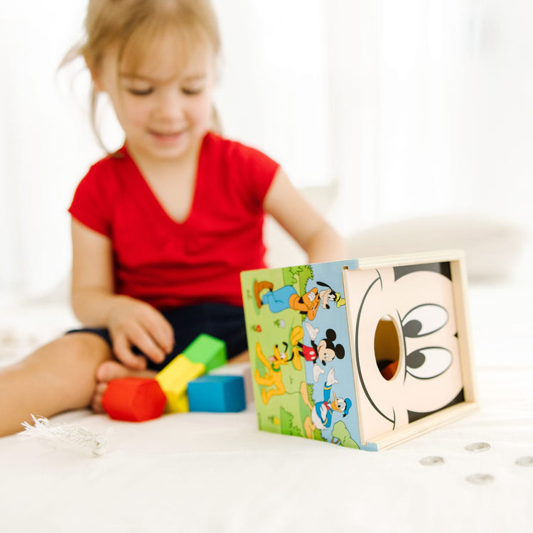 A kid playing with the Mickey Mouse & Friends Wooden Shape Sorting Cube
