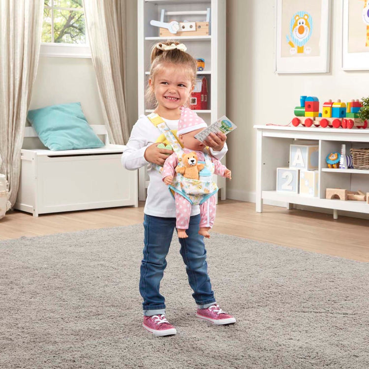 A kid playing with the Melissa & Doug Mine to Love Carrier Play Set for Baby Dolls with Toy Bear, Bottle, Rattle, Activity Card