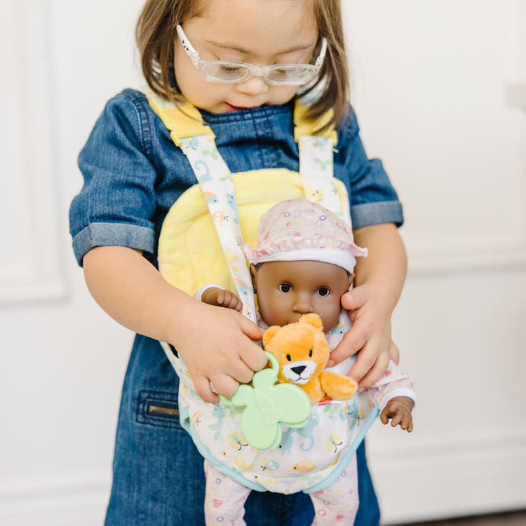 A kid playing with the Melissa & Doug Mine to Love Carrier Play Set for Baby Dolls with Toy Bear, Bottle, Rattle, Activity Card