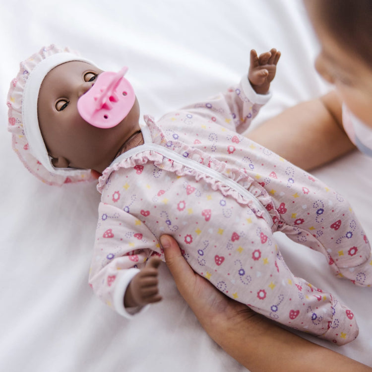 A kid playing with the Melissa & Doug Mine to Love Gabrielle 12" Poseable Baby Doll With Romper, Hat, Pacifier