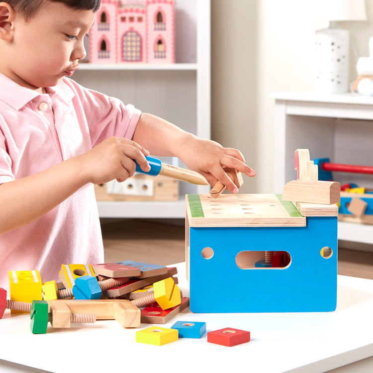 A kid playing with the Melissa & Doug Hammer and Saw Tool Bench - Wooden Building Set (32 pcs)