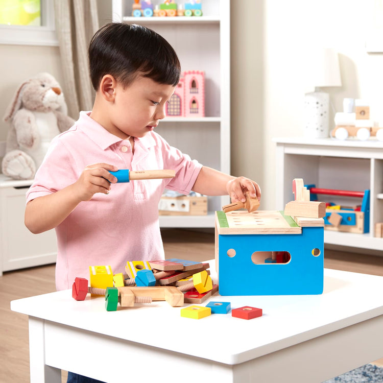 A kid playing with the Melissa & Doug Hammer and Saw Tool Bench - Wooden Building Set (32 pcs)