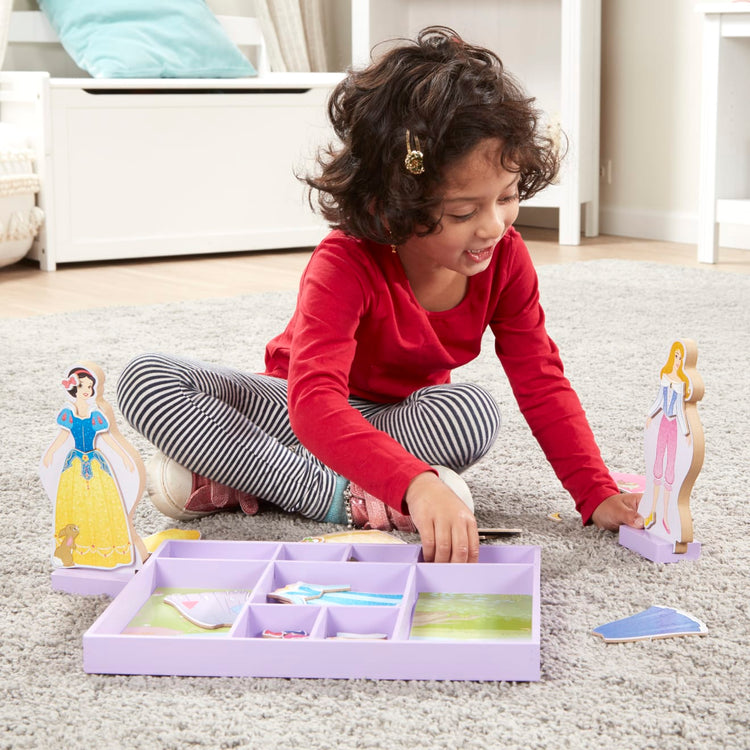 A kid playing with the Melissa & Doug Disney Sleeping Beauty and Snow White Magnetic Dress-Up Wooden Doll Pretend Play Set (40+ pcs)