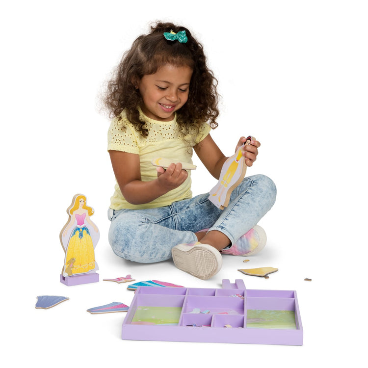 A child on white background with the Melissa & Doug Disney Sleeping Beauty and Snow White Magnetic Dress-Up Wooden Doll Pretend Play Set (40+ pcs)