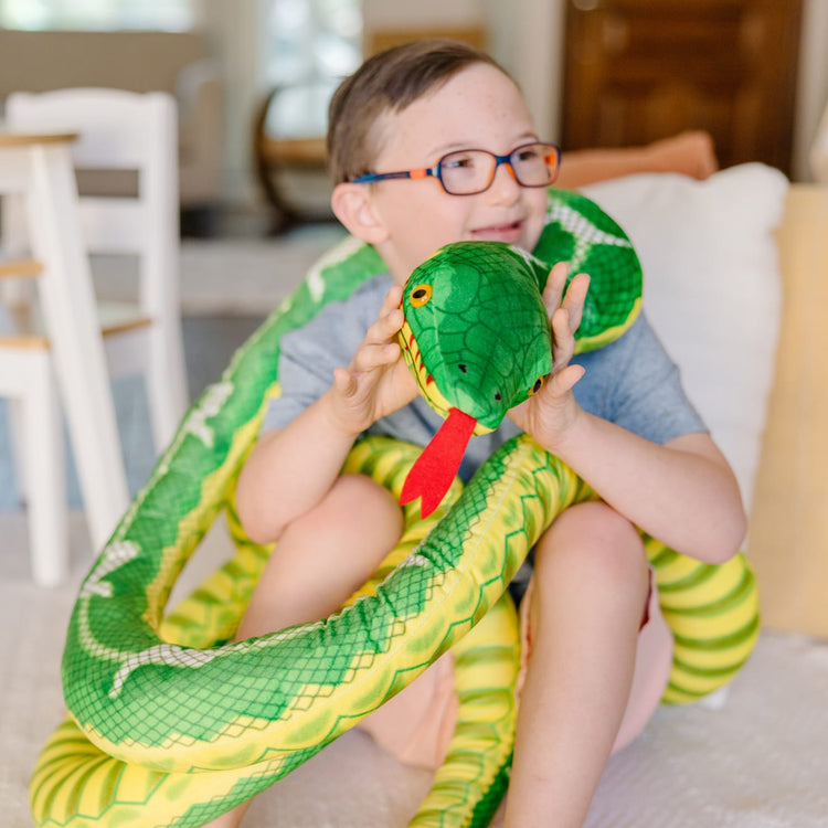 A kid playing with the Melissa & Doug Giant Boa Constrictor - Lifelike Stuffed Animal Snake (over 14 feet long)
