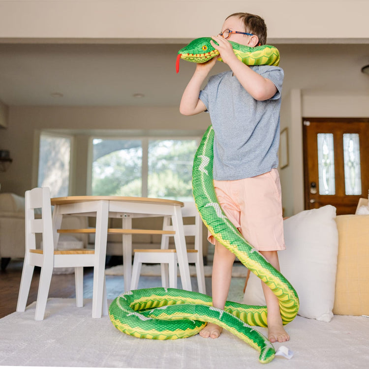 A kid playing with the Melissa & Doug Giant Boa Constrictor - Lifelike Stuffed Animal Snake (over 14 feet long)