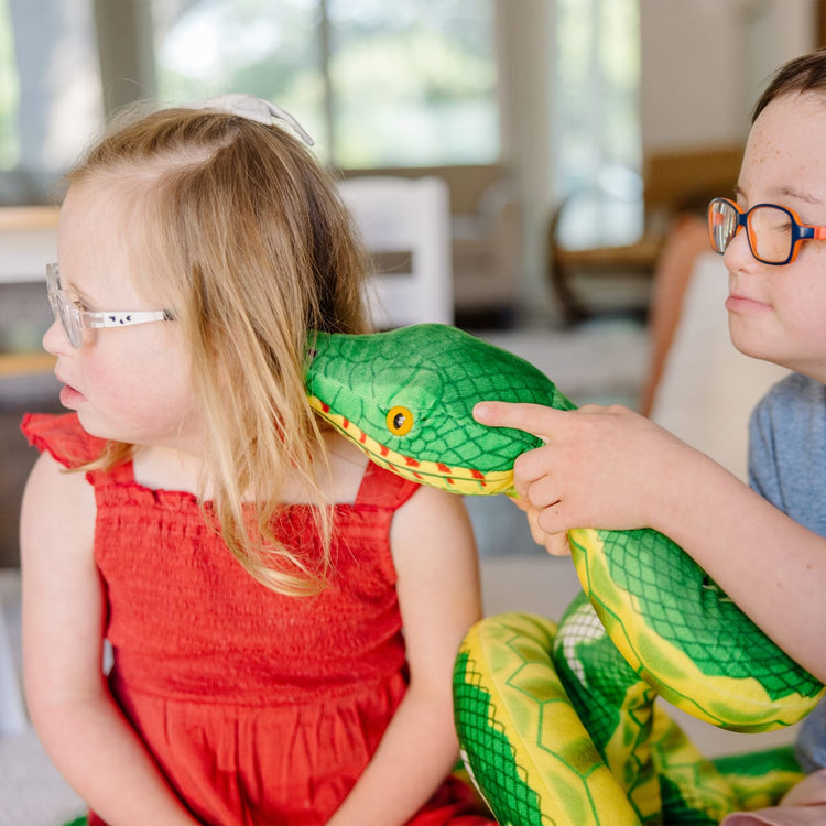 A kid playing with the Melissa & Doug Giant Boa Constrictor - Lifelike Stuffed Animal Snake (over 14 feet long)