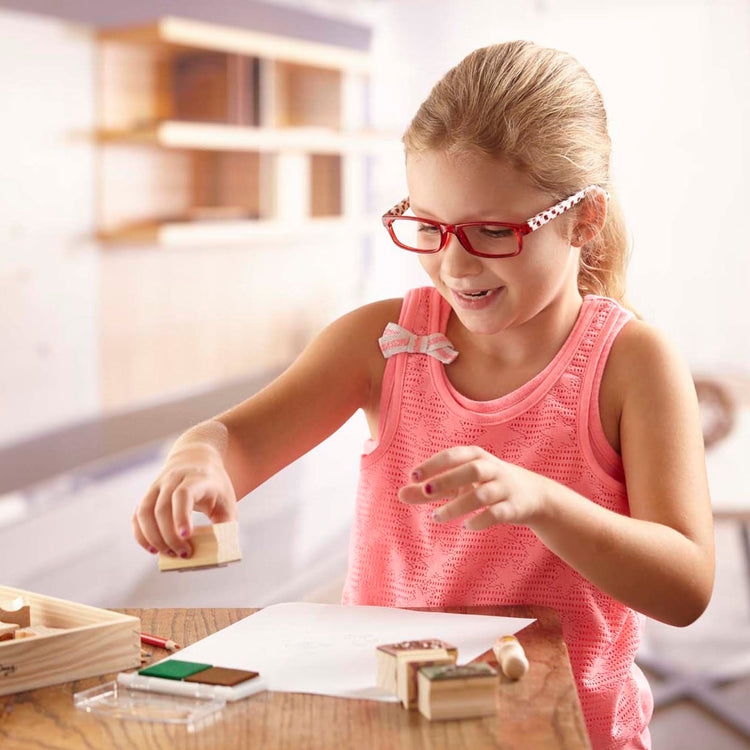 A kid playing with the Melissa & Doug Stamp-a-Scene Wooden Stamp Set: Farm - 20 Stamps, 5 Colored Pencils, and 2-Color Stamp Pad