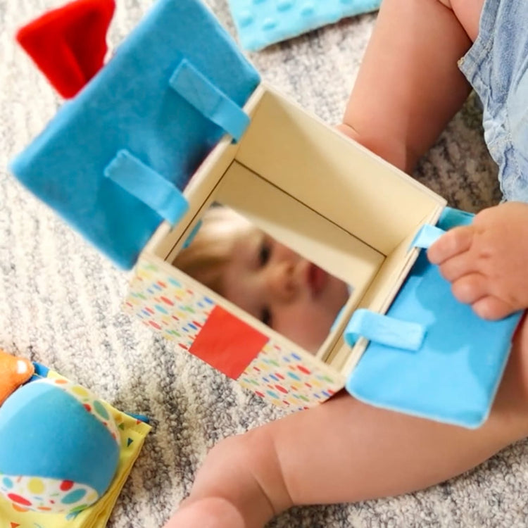A kid playing with the Melissa & Doug Wooden Surprise Gift Box Infant Toy (5 Pieces)
