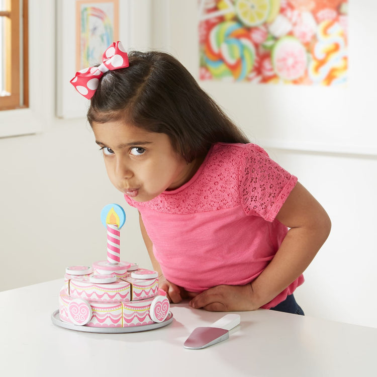 A kid playing with the Melissa & Doug Triple-Layer Party Cake Wooden Play Food Set