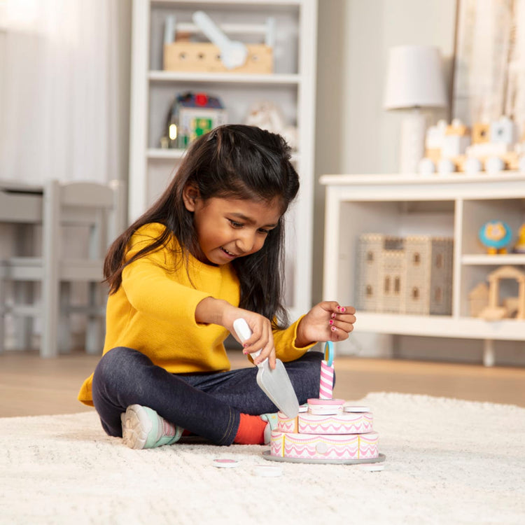 A kid playing with the Melissa & Doug Triple-Layer Party Cake Wooden Play Food Set