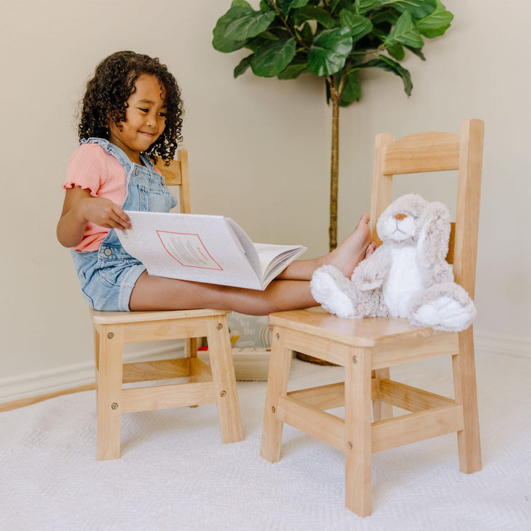 A kid playing with the Melissa & Doug Solid Wood Chairs, Set of 2 - Light Finish Furniture for Playroom
